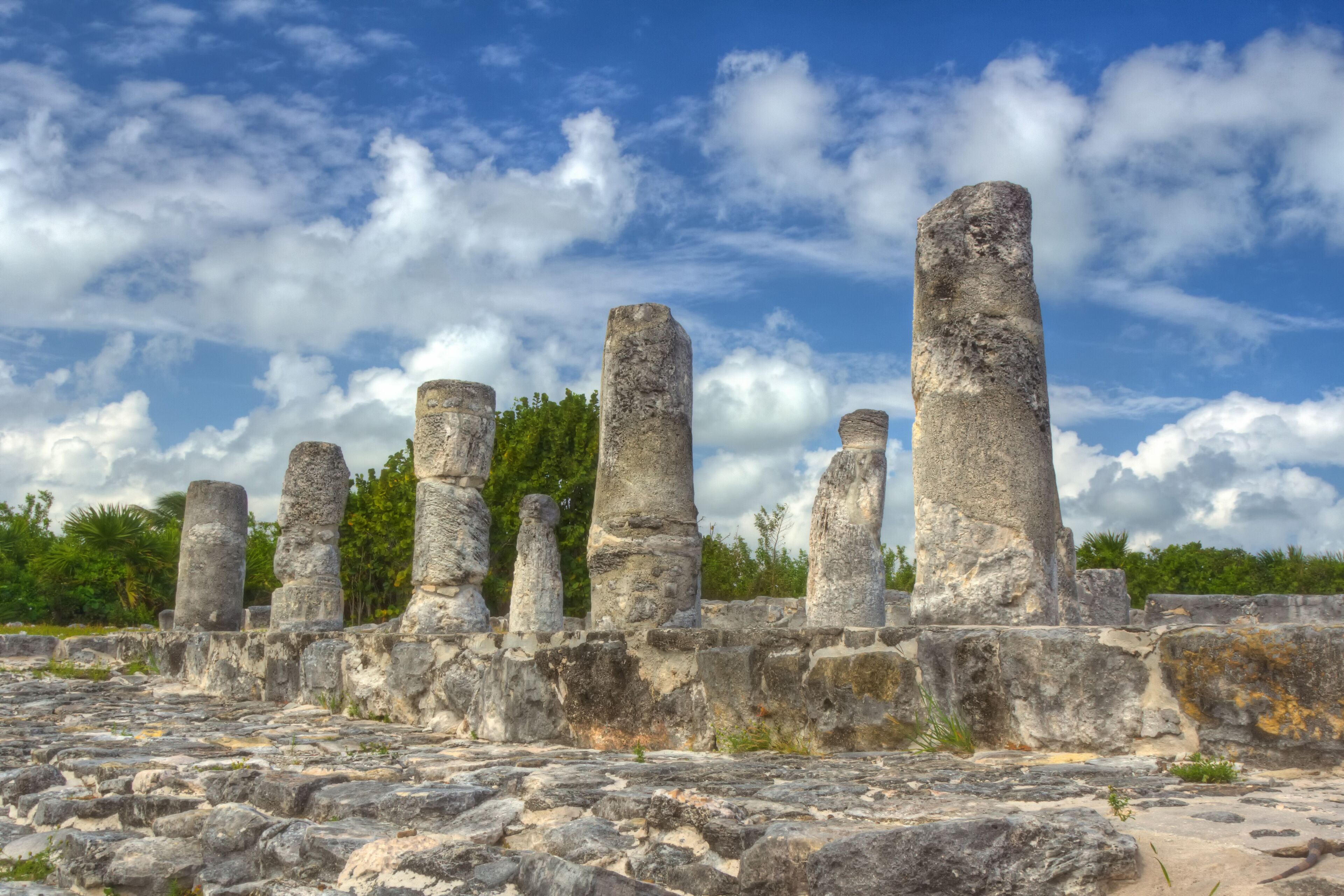 Ancient stone pillars and ruins under a partly cloudy sky.