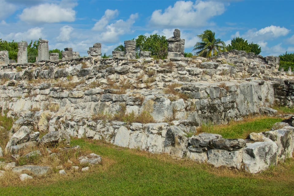 Antiguas ruinas de piedra con columnas y una zona cubierta de césped.
