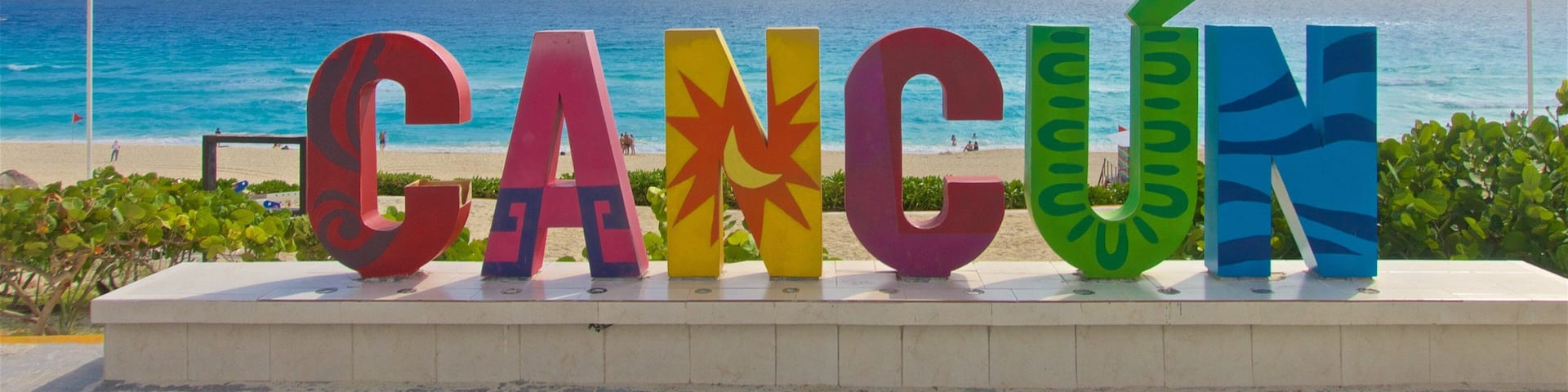 Une plage où le mot « CANCÚN » est écrit en lettres colorées.
