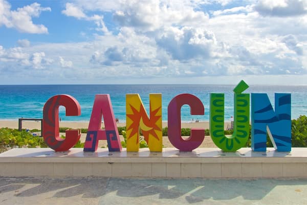 En strand med ordet "CANCÚN" stavet med farverige bogstaver.