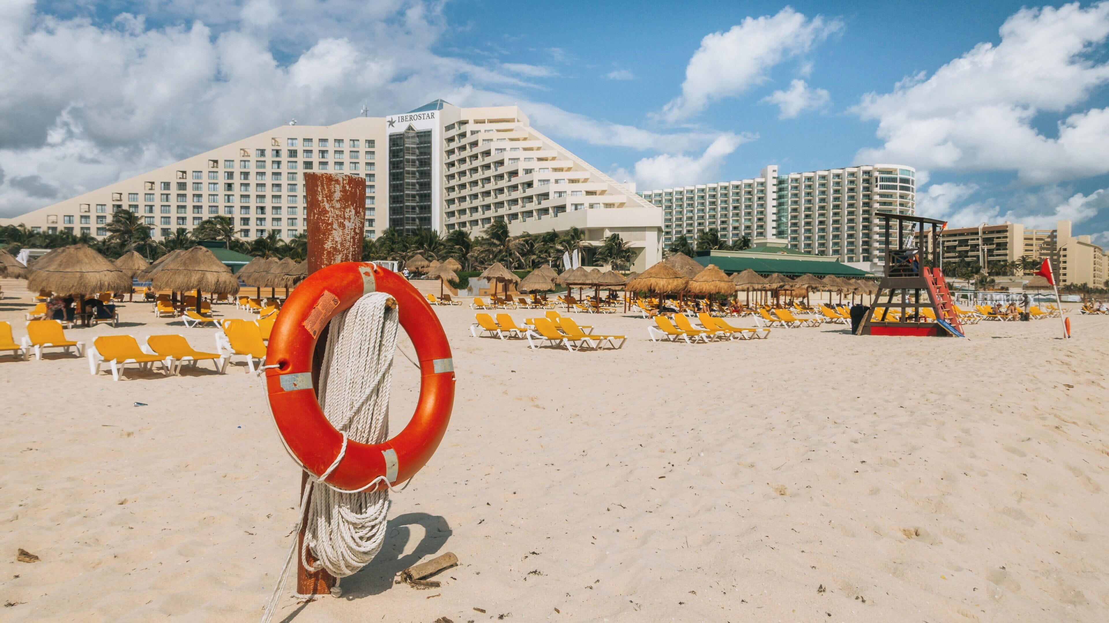 Vibrant Delfines Beach in Cancun showcases golden sand and cozy sun loungers against a backdrop of towering hotels