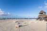 Een strand met rijen ligbedden en een constructie met rieten dak.