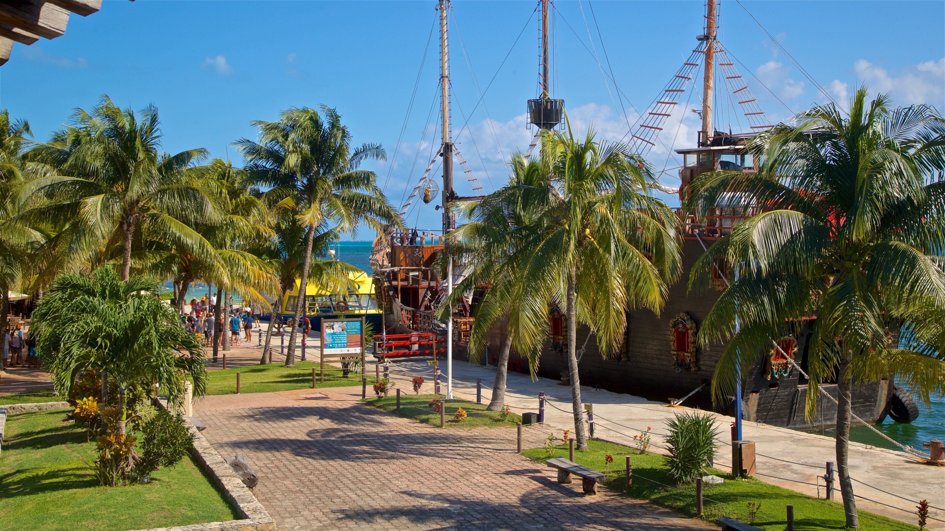 Un parque con temática pirata, que incluye un barco grande, palmeras y una zona de playa.