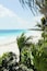 A beach with clear turquoise water, white sand, and lush green palm trees.