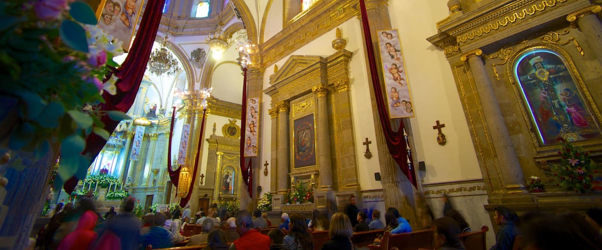 An ornate church interior with high ceilings, golden decorations, and a congregation of people.