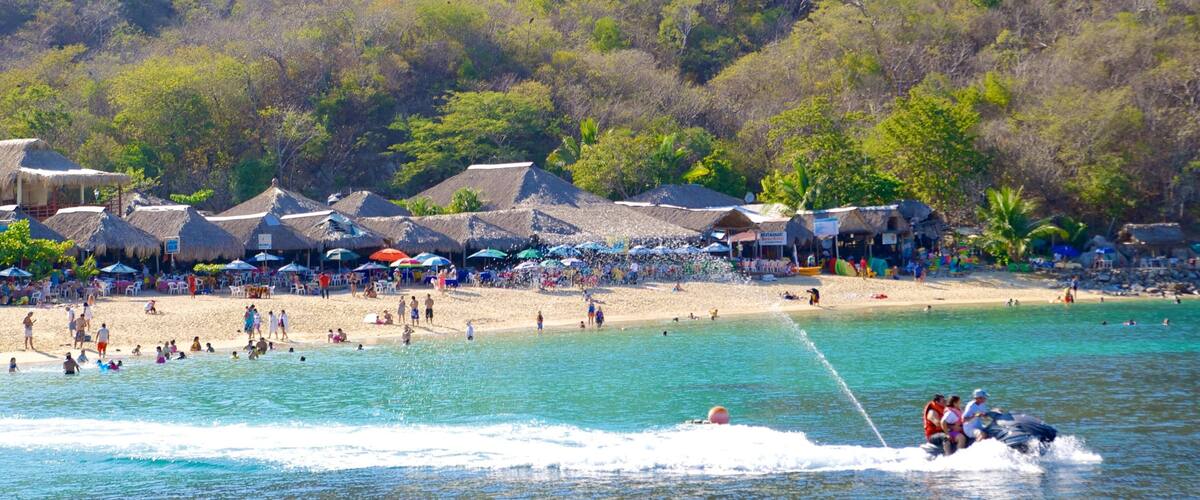 Playa La Entrega ofreciendo una playa de arena, una ciudad costera y jet ski