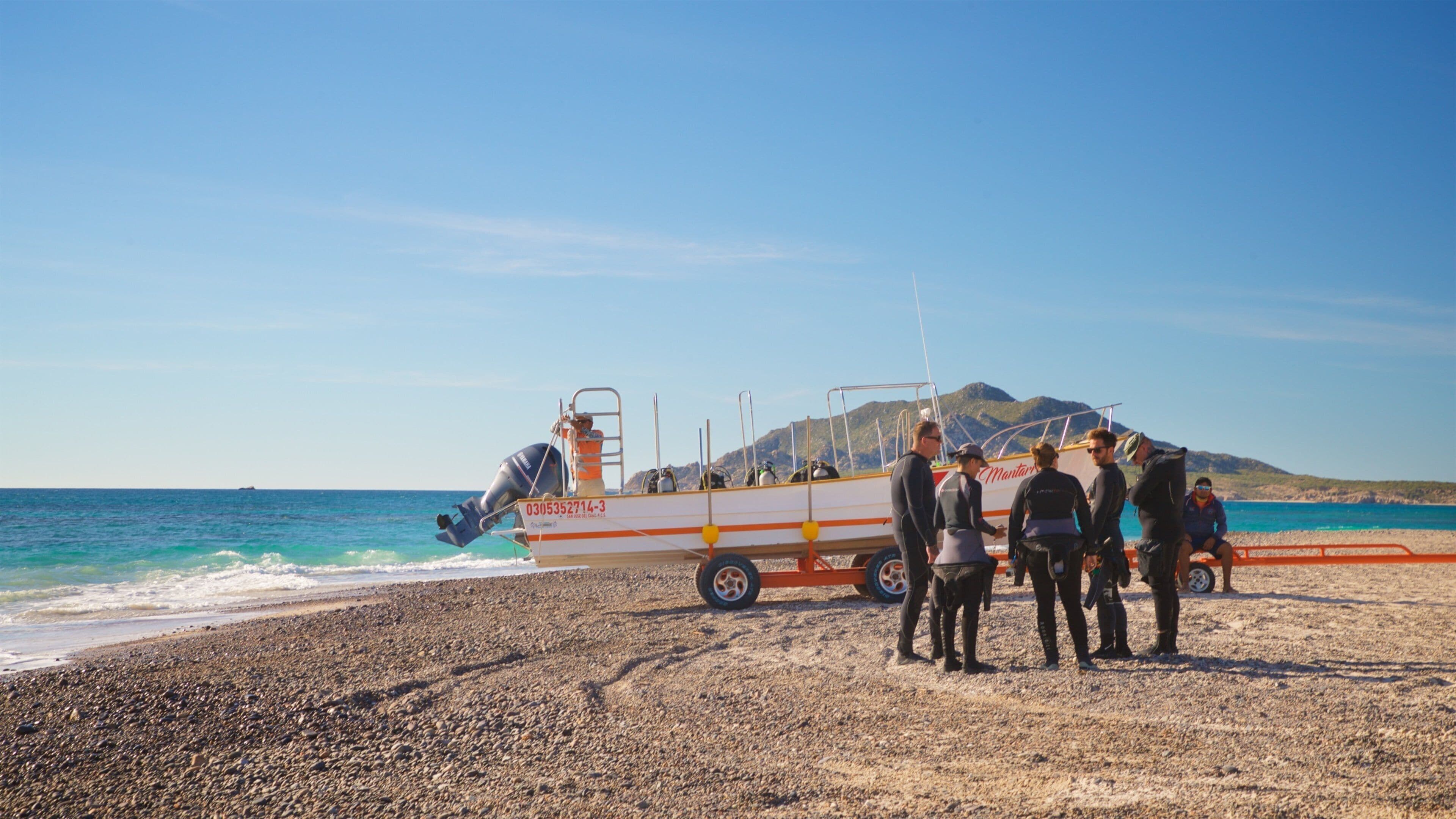 Una playa con un bote salvavidas y gente de pie en la orilla.
