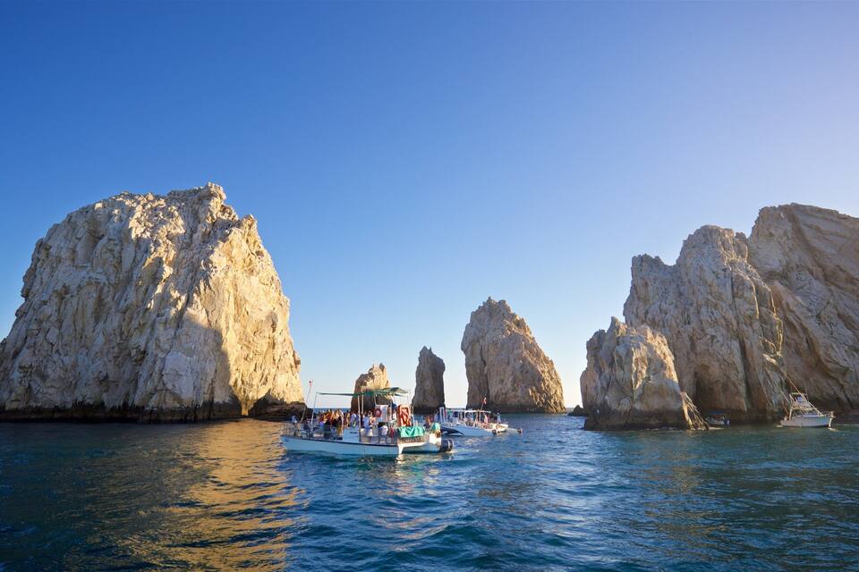A boat tour with tourists near large rock formations in the sea.