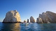 A boat tour with tourists near large rock formations in the sea.