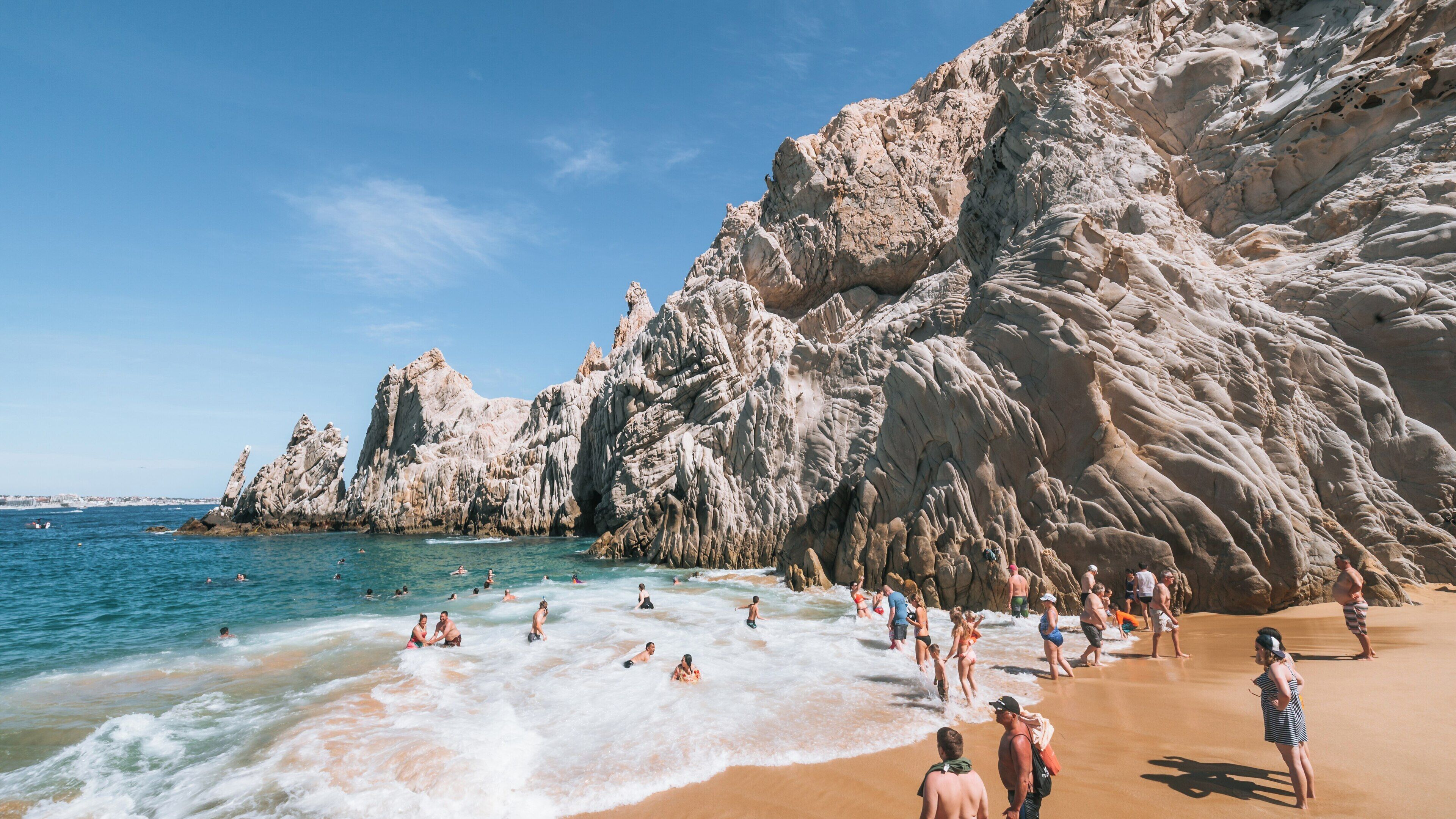 Visitors enjoy warm sun and clear waters at Lover's Beach in Cabo San Lucas, Baja California Sur, Mexico during a beautiful summer day