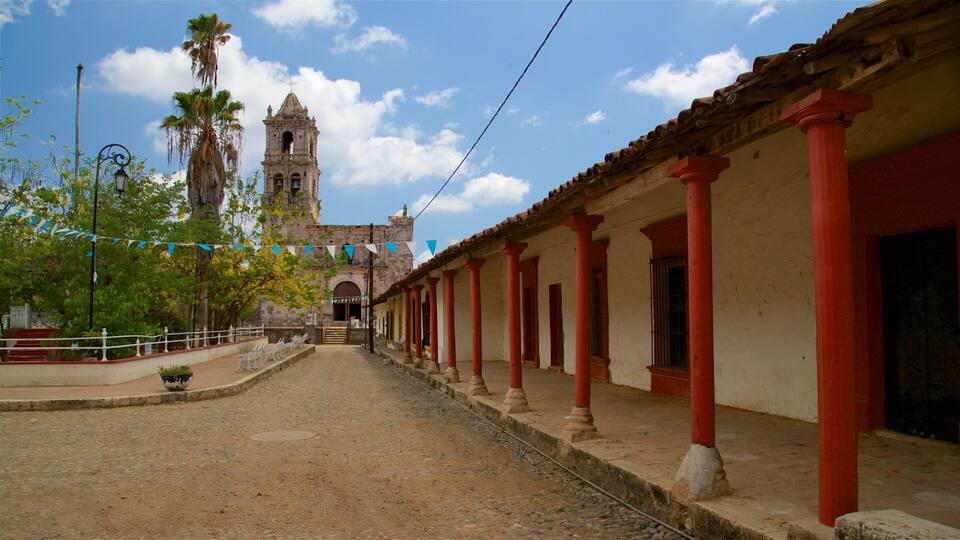 A colonial-style building with red columns and a bell tower in the background.