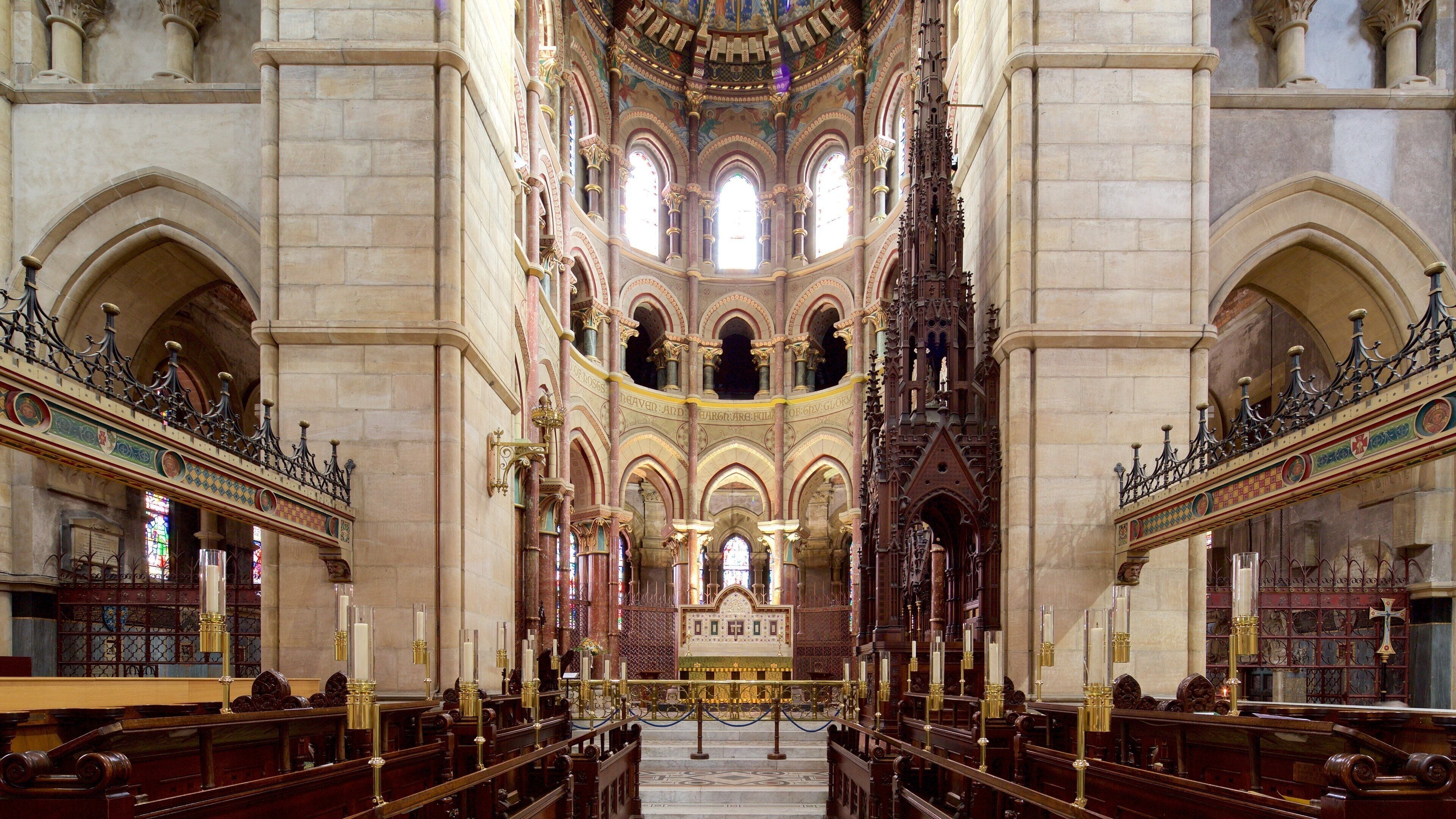 Interior de una iglesia ornamentada con altos techos abovedados, vidrieras y un altar central.