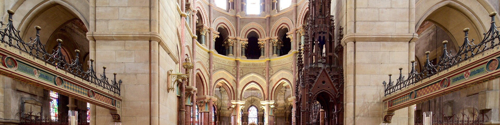 Interior de una iglesia ornamentada con altos techos abovedados, vidrieras y un altar central.