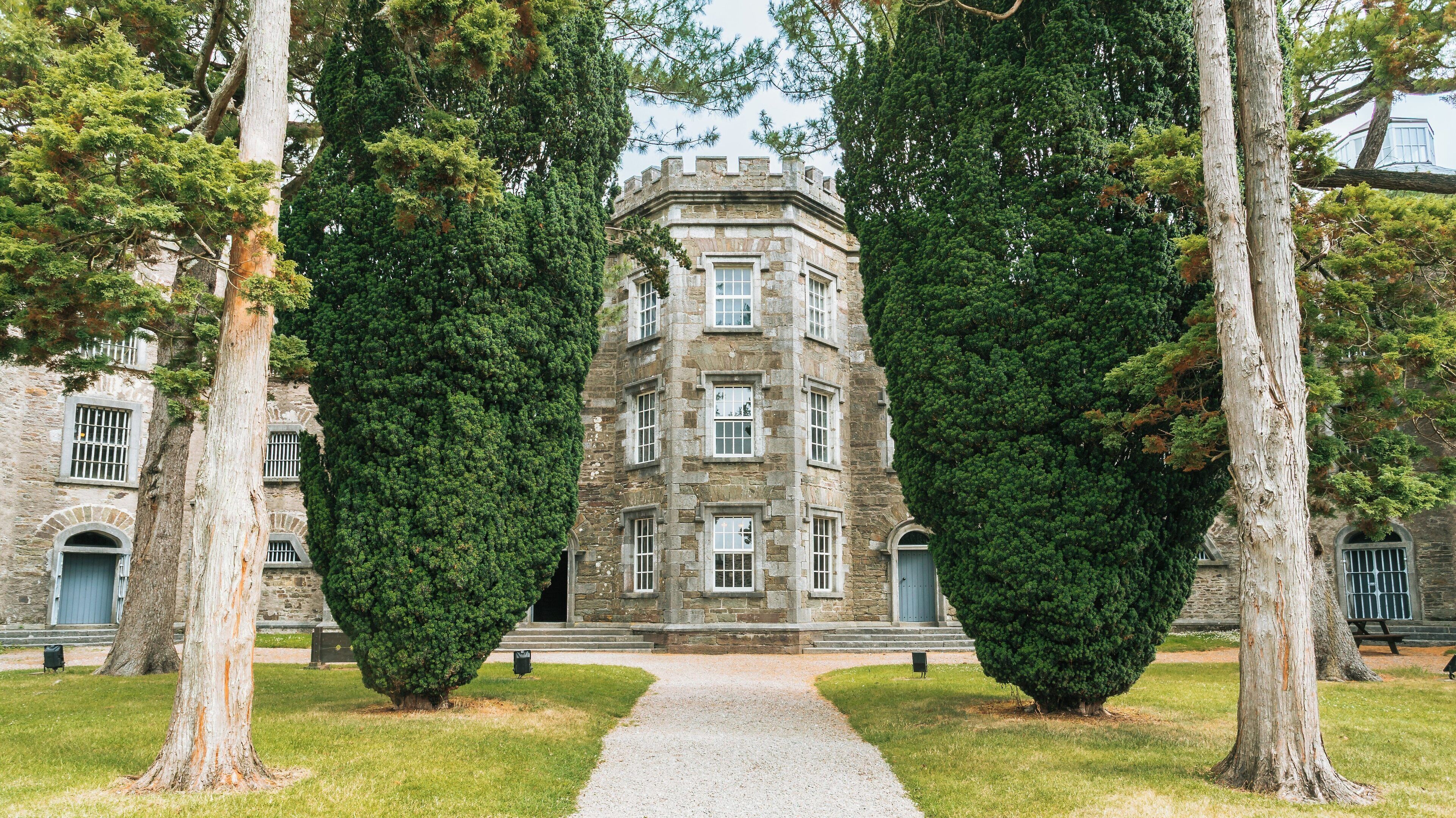 Historic Cork City Gaol surrounded by lush greenery in County Cork, Ireland