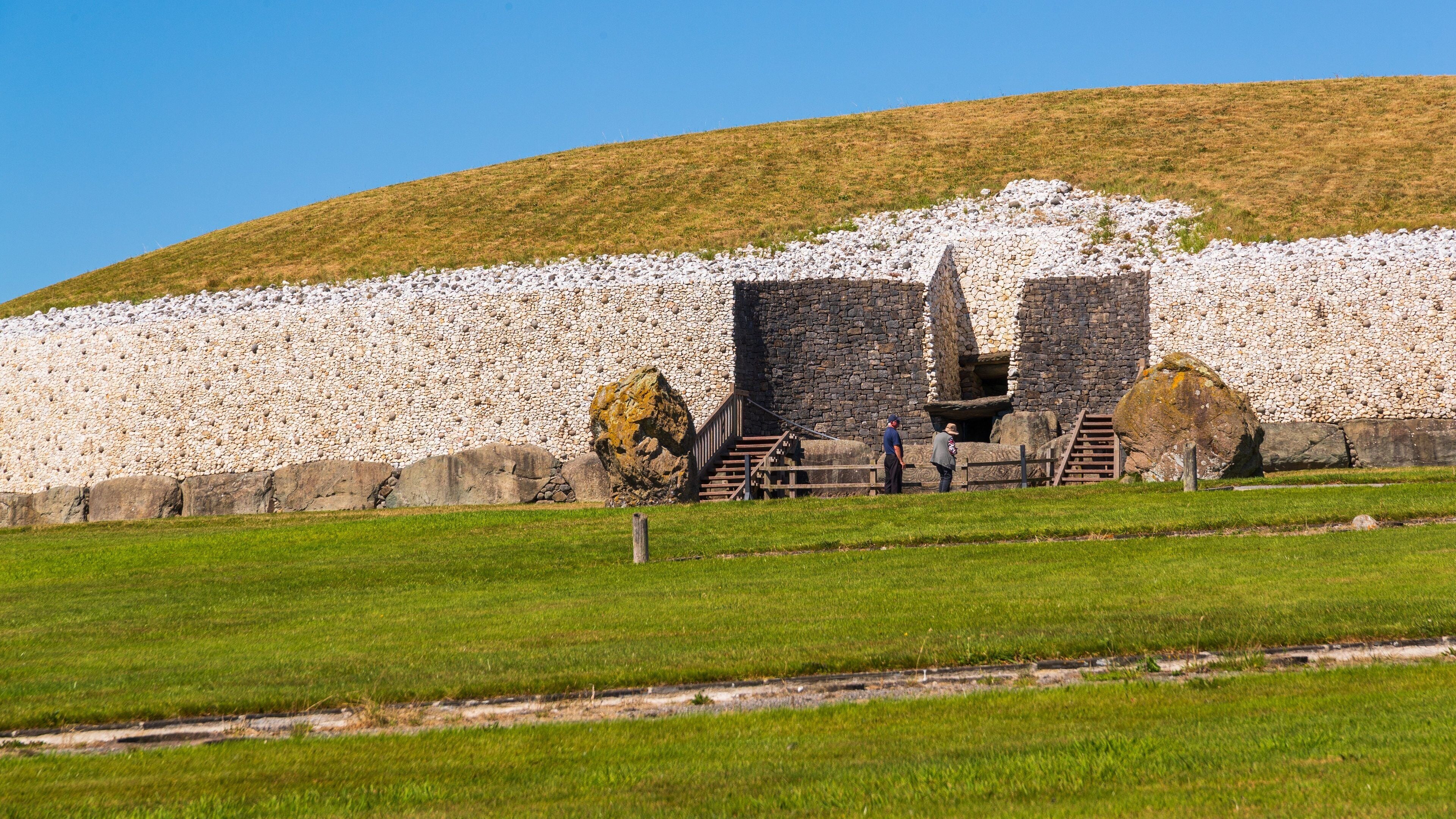 A stone wall with a staircase leading up to a stone structure.
