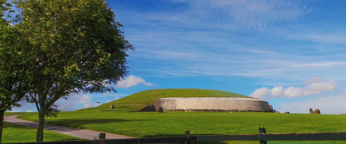 Newgrange is a prehistoric monument in County Meath. It was built during the Neolithic period around 3200 BC making it older than Stonehenge and the Pyramids. The site consists of a large circular mound with a stone passageway and interior chambers. The passage to the interior chamber it is aligned to face the rising sun and its light floods the chamber ONLY for a few days each side of dawn on the winter solstice.