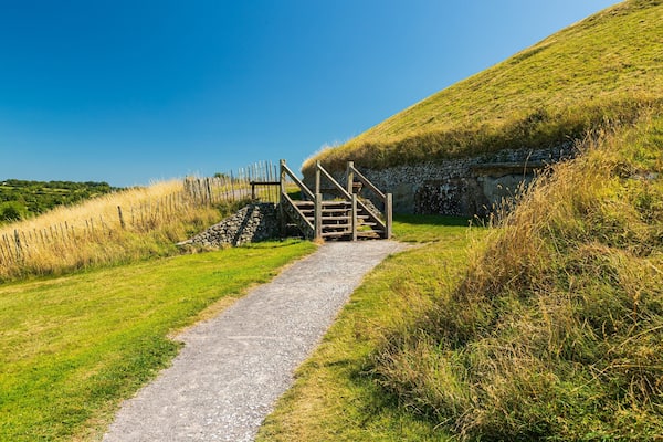A gravel path leading to a wooden staircase on a grassy hill.