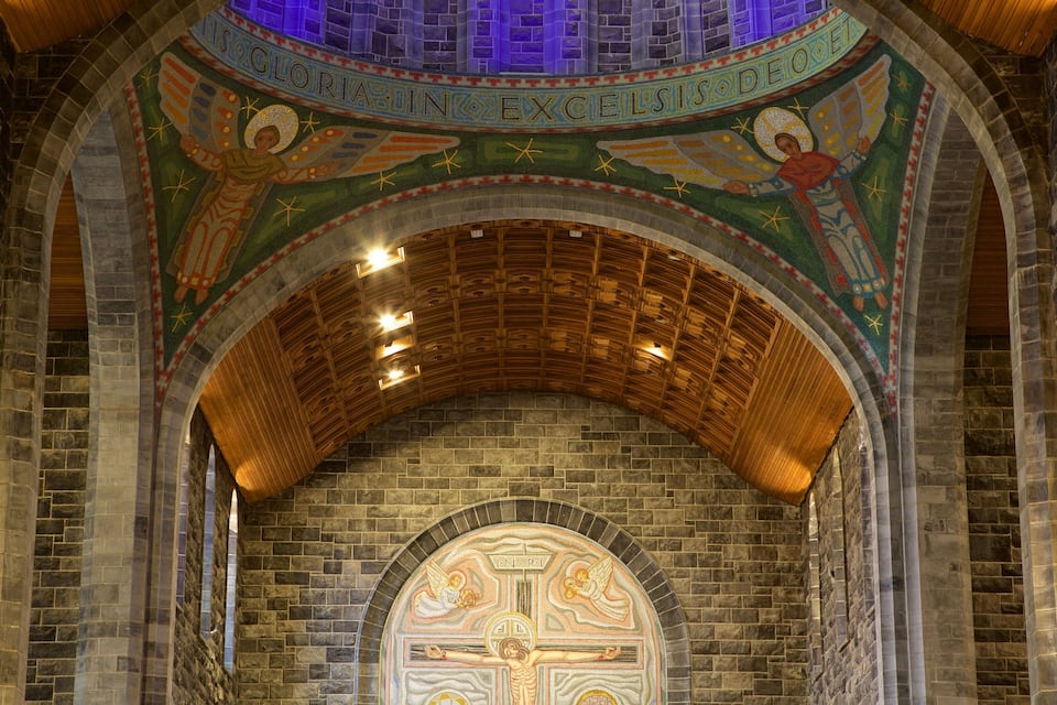 Interior de una iglesia con techo de mosaicos y una cruz.