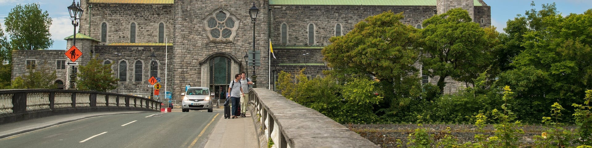 A historic stone building with a green dome and a clock tower.