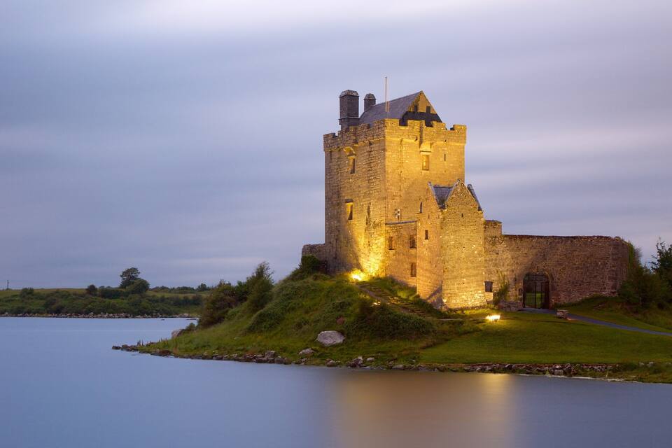 Un château perché sur une colline verdoyante, dominant un lac paisible.
