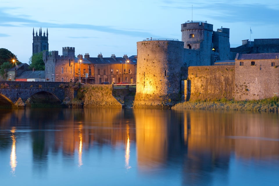 Un château historique, doté d’un fossé, d’un pont et d’une église en arrière-plan.