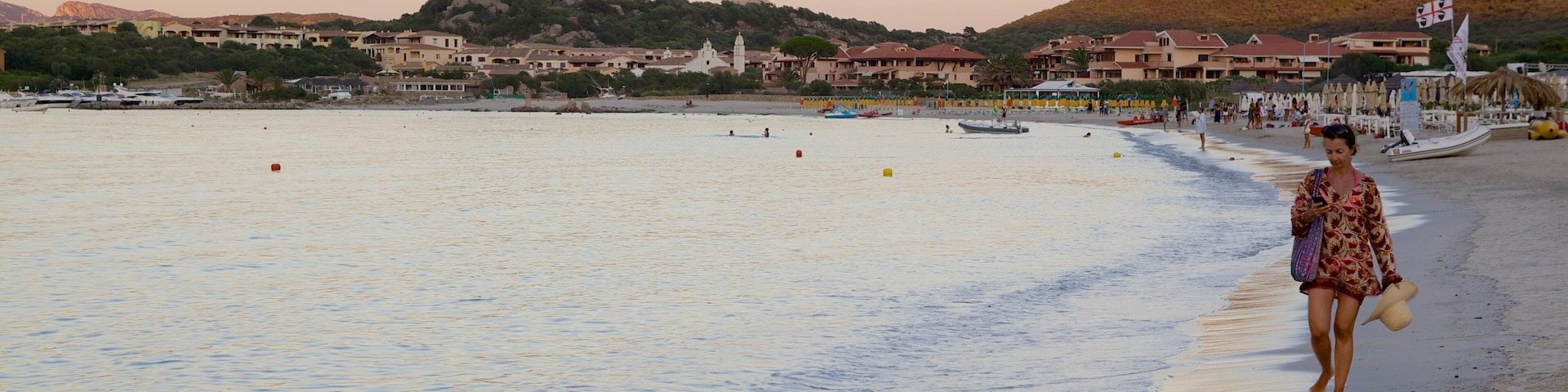 Praia de La Marinella caracterizando um pôr do sol, uma cidade litorânea e uma praia de areia