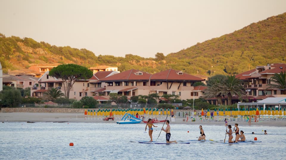 A beach with paddleboarders, a boat, and buildings in the background.