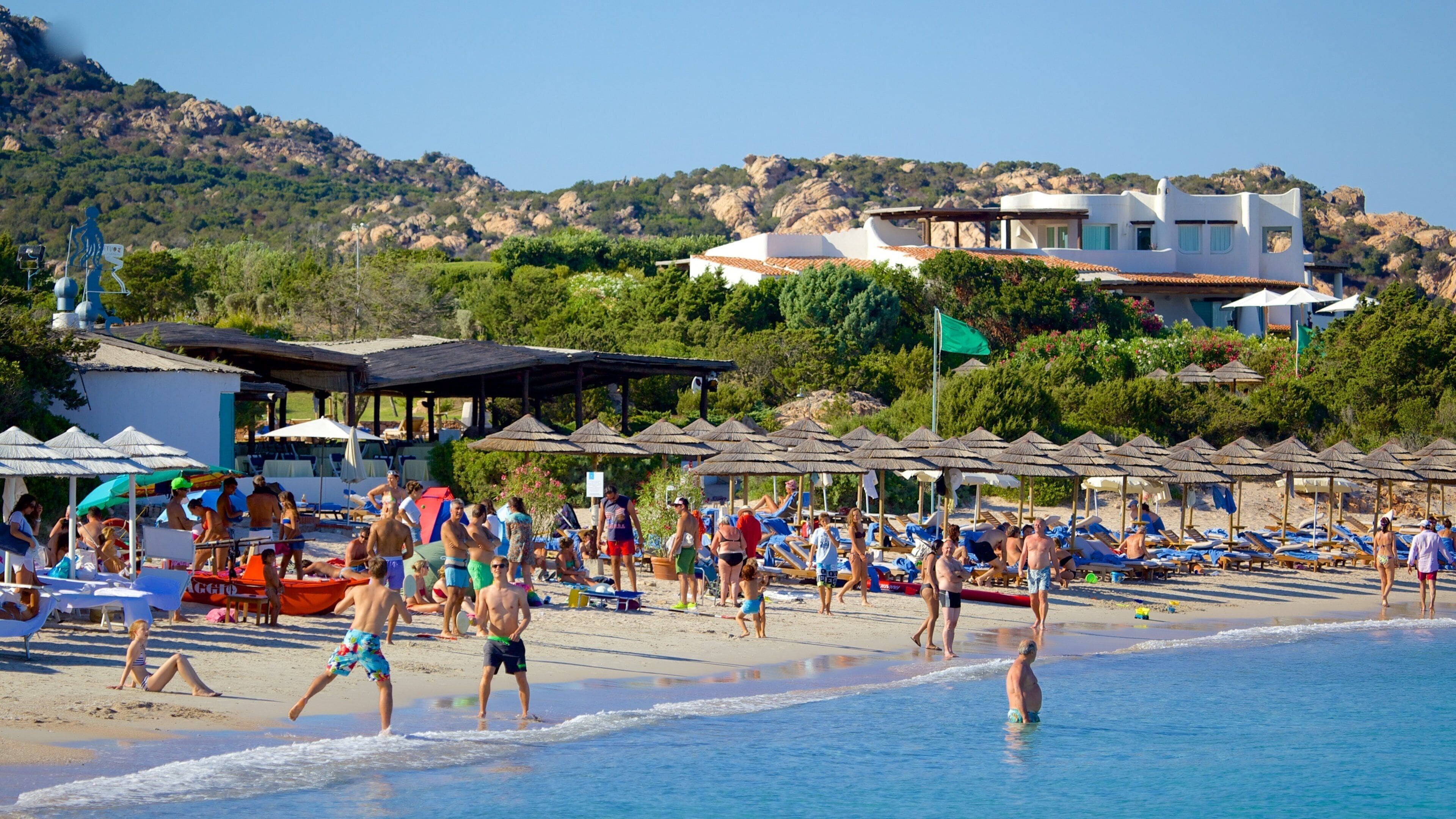 Romazzino Beach featuring a sandy beach as well as a large group of people