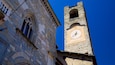 A historic stone tower with a clock and arched windows.