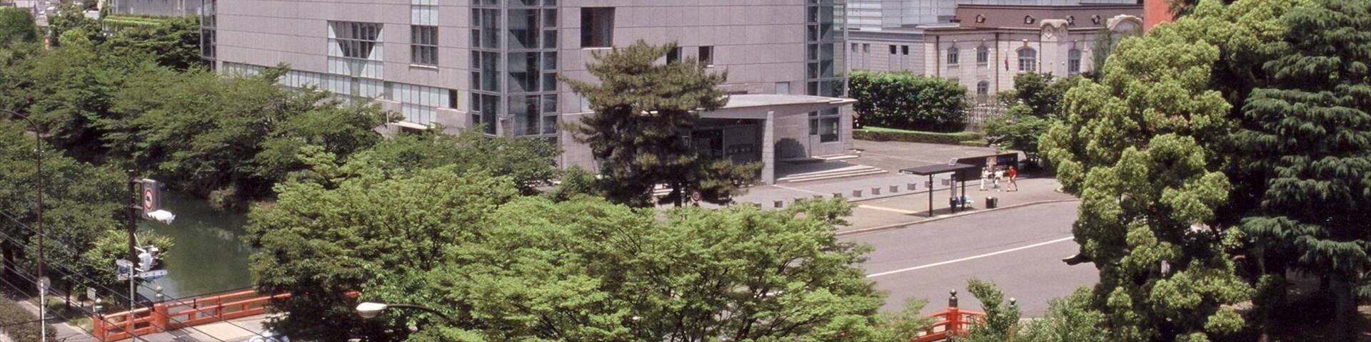 A modern building with large windows and a red torii gate in the foreground.