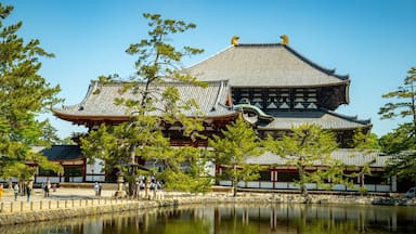 A traditional Japanese temple with a large pond in front.