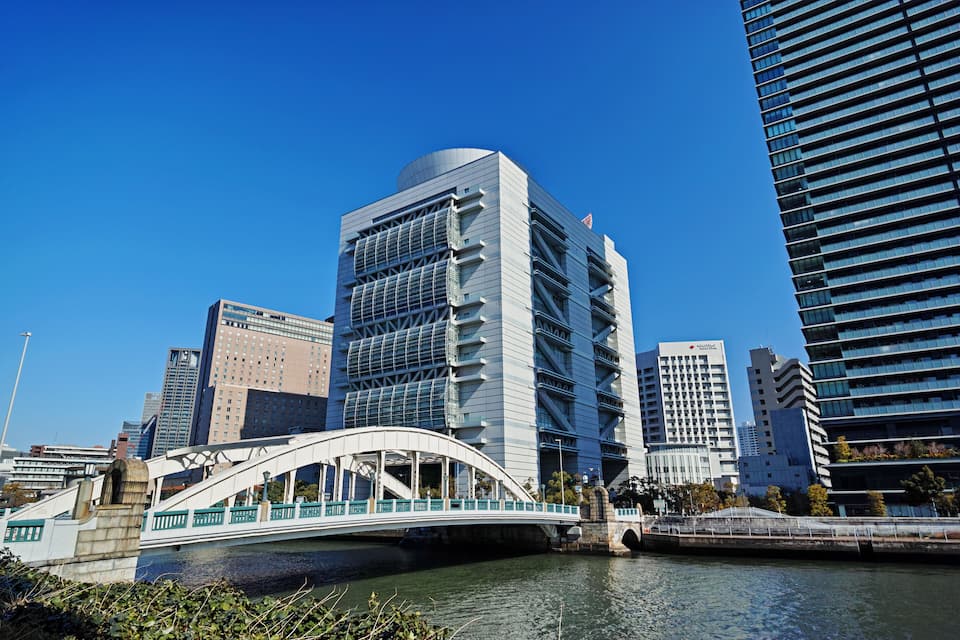 A modern cityscape with a distinctive bridge over a river, surrounded by high-rise buildings.