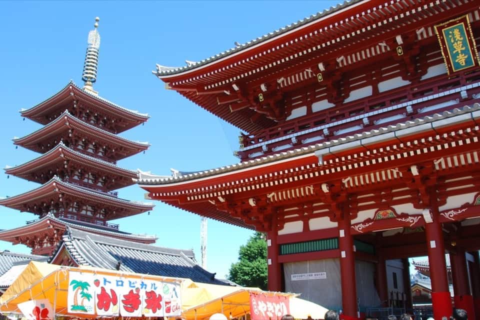 En traditionell japansk pagod med flera våningar och en röd byggnad med utsmyckade detaljer.