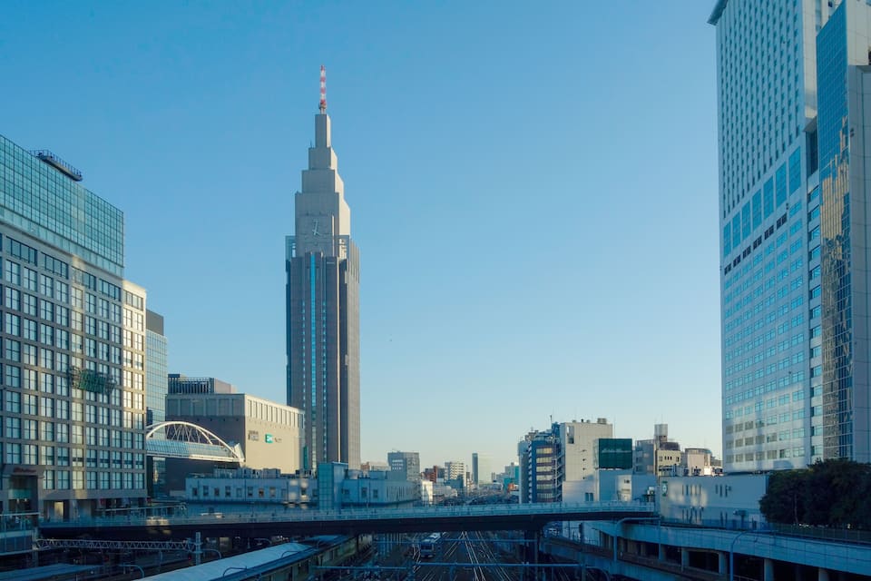 Paisagem urbana com um arranha-céu imponente, uma ponte e edifícios modernos ao redor.
