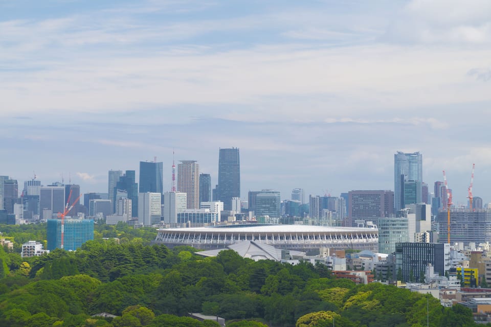 Stadsbeeld met moderne wolkenkrabbers, een groot stadion en omliggend groen.