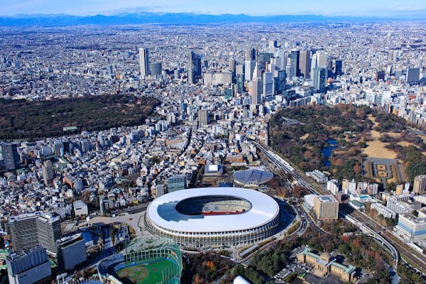 Paisagem urbana com um estádio grande, cercado por edifícios urbanos densos e uma área de parque.