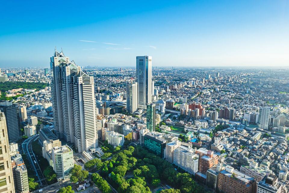 A cityscape with high-rise buildings, a dense urban area, and a clear blue sky.