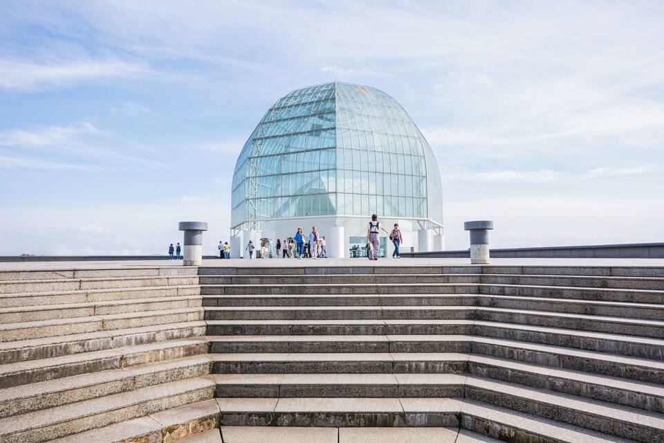 Una gran estructura en forma de cúpula de cristal con una escalera que conduce hacia ella.