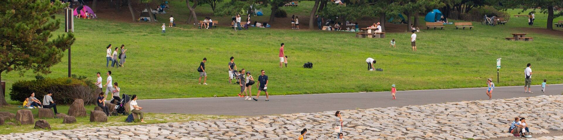 A park with a large glass dome structure, picnic areas, and a stone wall.