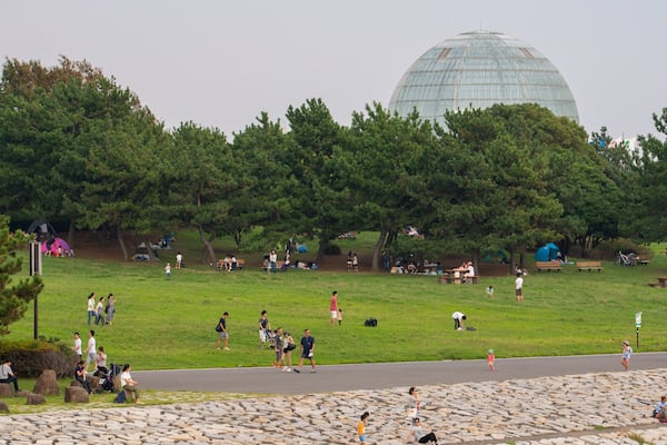 A park with a large glass dome structure, picnic areas, and a stone wall.