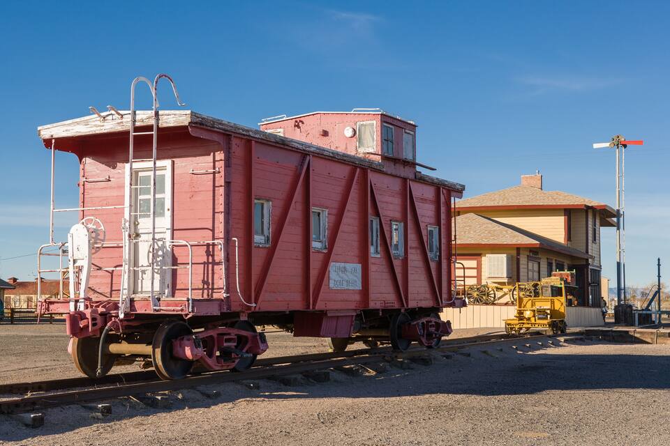 A red caboose train car with a ladder and a sign that reads "THANK YOU DON'T FEEL."