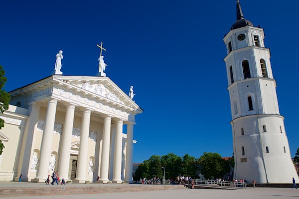 A neoclassical building with columns and statues, and a tall tower with a clock.