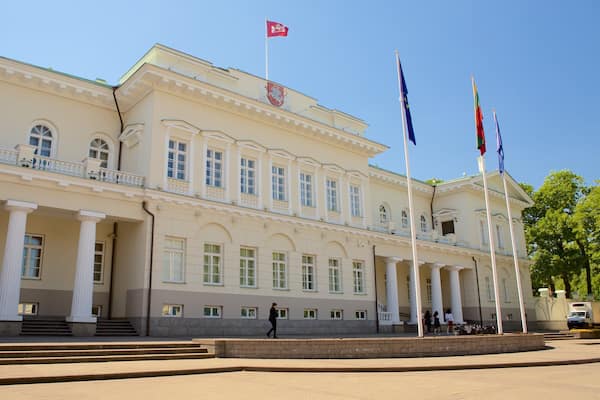 A large, classical building with columns and flags.