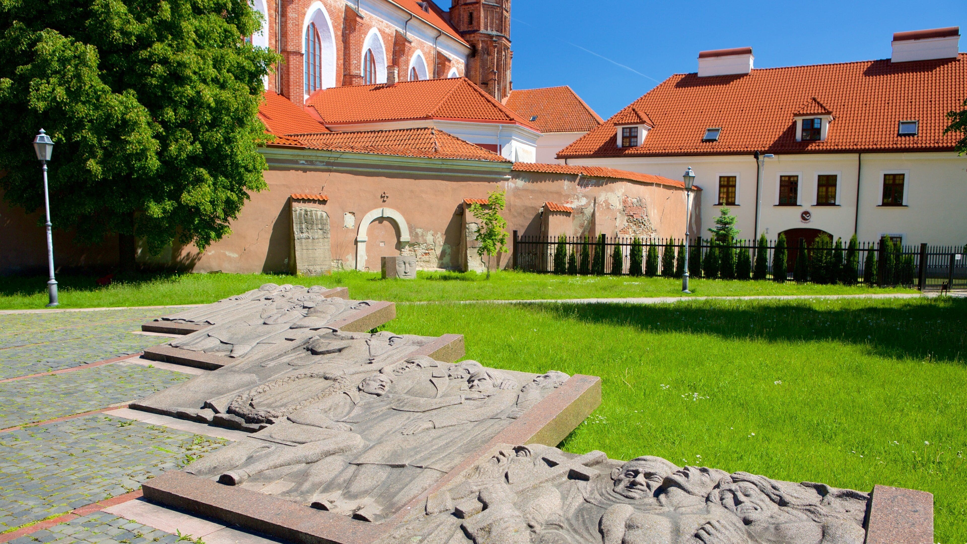 A historical site with ancient stone carvings, a church with red-tiled roofs, and a well-maintained lawn.