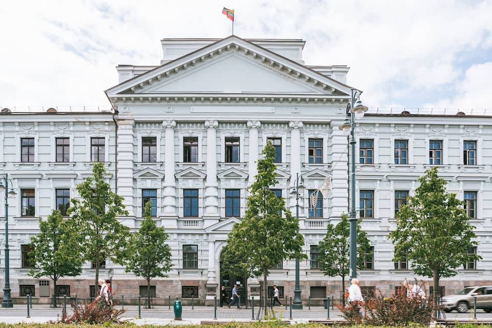 A large white building with columns and a flag on top.