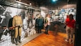 A museum exhibit with mannequins in military uniforms, a rifle, and a backdrop of historical photographs.