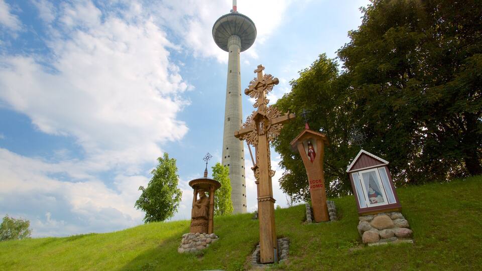 Ein hoher Turm mit einer kugelförmigen Aussichtsplattform, umgeben von hölzernen Kreuzen und einem kleinen Schrein.
