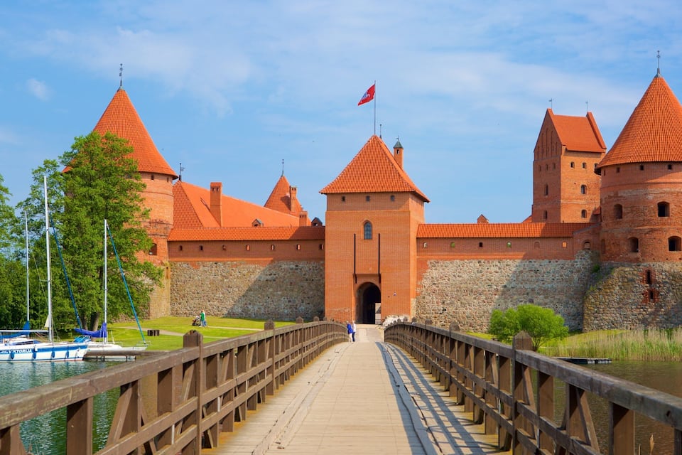 A historic castle with red-tiled roofs and a wooden bridge leading to it.
