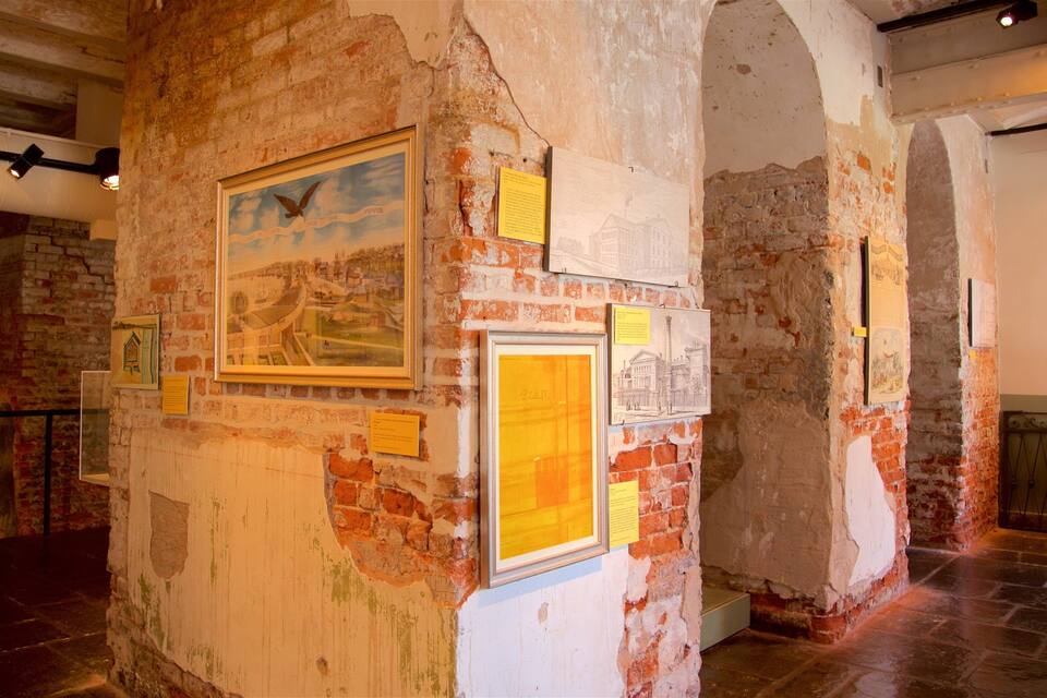 A historical building interior with exposed brick walls, framed historical documents, and a bird illustration.