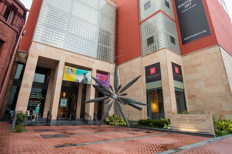 The entrance to the Ogden Museum of Southern Art, featuring a large metal sculpture and the museum's signage.